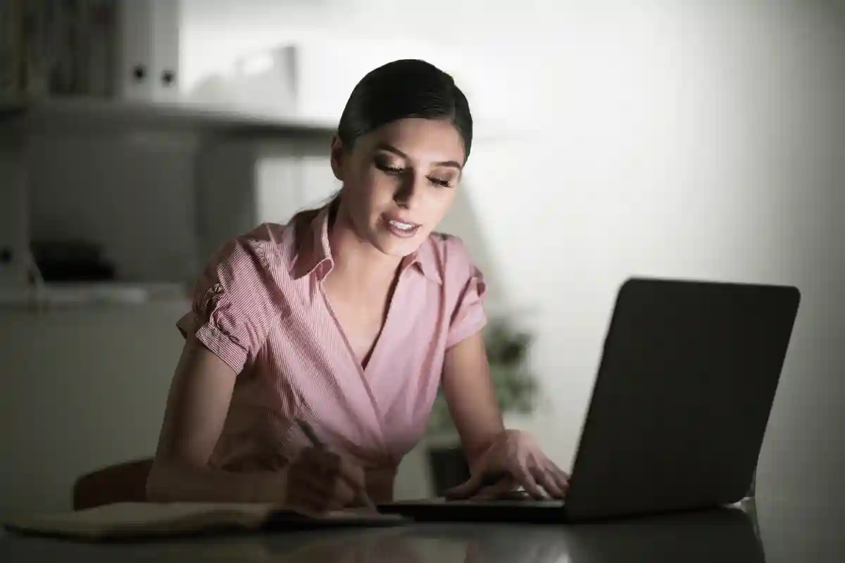 seorang wanita berkemeja merah muda depan laptop